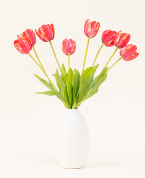 Silke kunstige blomsterbuket French Tulip red er arrangeret i en hvid keramisk vase med otte røde og gule tulipaner med grønne blade mod en almindelig lys baggrund.