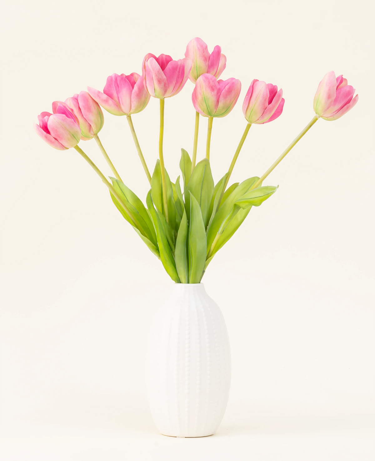 Silke kunstige blomsterbuketten French Tulip pink er arrangeret i en hvid vase med lyserøde franske tulipaner og grønne blade mod en enkel lys baggrund.