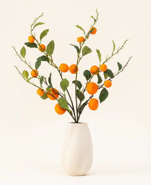 Silk kunstige blomsterbuket Mandarin har en hvid tekstureret vase og grene af grønne blade og levende orange kunstige mandariner, som tilføjer et livligt præg mod en almindelig lys baggrund.