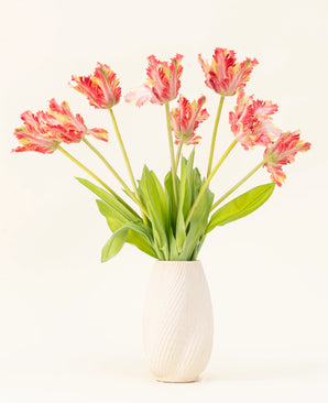 En vase med hvid struktur viser Silke kunstige blomsterbuket French Parakeet Tulip rød/gul, med naturtro røde og gule tulipaner med grønne blade mod en almindelig lys baggrund.