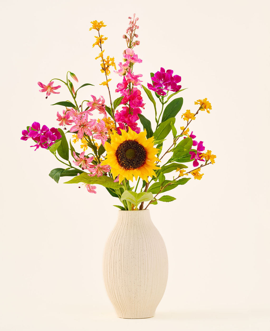 Den kunstige silkeblomstbuket 'Tiny Sunshine' er placeret i en beige keramikvase, bestående af en kunstig buket af naturtro blomster, såsom en stor solsikke, pink og magenta blomster og gule blomster med grønne blade, mod en almindelig lys baggrund. Dette arrangement fra Easyplants består af smukke silkeblomster, der tilføjer langvarig skønhed til ethvert rum.