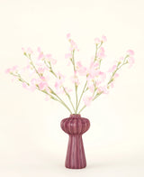 Silk kunstige blomsterbuketten Pea light pink, med flere lys pink ærtestilke i en ribbet bordeaux vase, står på en bleg baggrund - ideel til ethvert kunstigt blomsterinteriør.