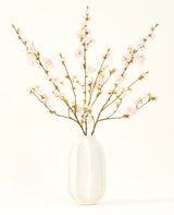 Silke kunstige blomsterbuketten Cherry blossom lys pink 94 cm har sarte pink kunstige kirsebær blomster i en hvid keramik vase, som tilføjer elegance mod en almindelig lys baggrund.