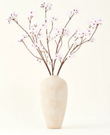 Silke kunstige blomsterbuketten Cherry blossom lys pink 114 cm står i en høj beige keramik vase med lange, tynde grene og sarte lys pink blomster, hvilket skaber en fredfyldt kunstig blomsteraccent mod en almindelig baggrund.
