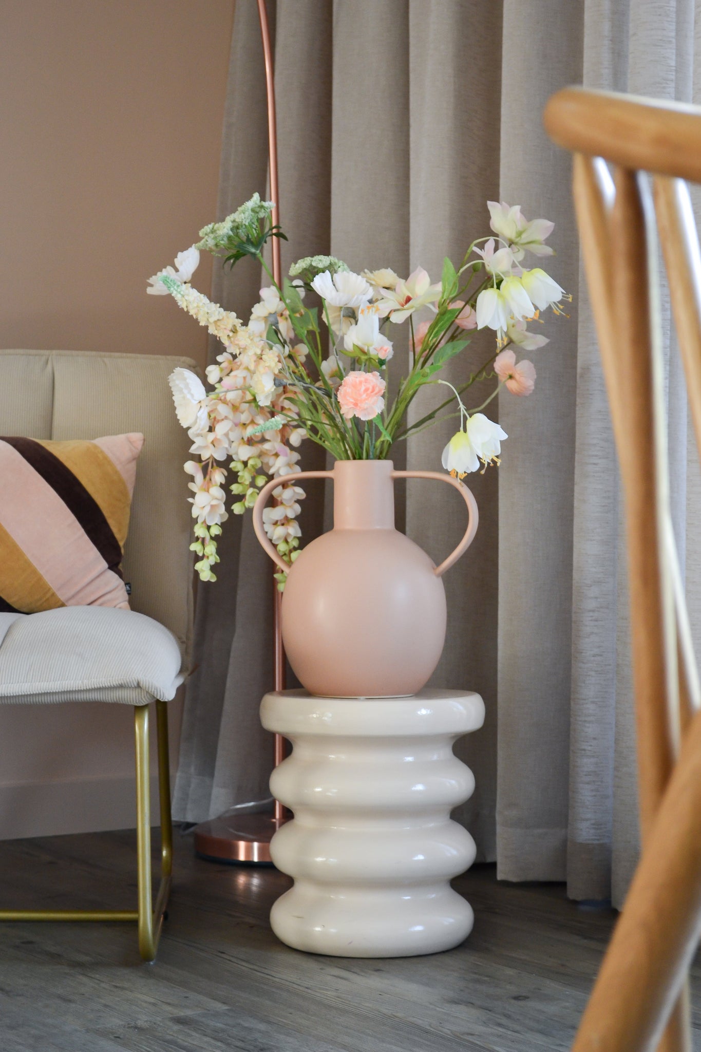 Artificial Flower Fritillary 94 cm hvid står i en lys pink keramikvase med hanke, placeret på en bølget hvid base ved siden af en moderne stol med stribet hynde og neutrale gardiner i et stilfuldt rum.
