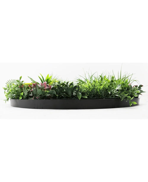 Den kunstige hæk på sort ramme Ø100 cm er en sort, halvcirkelformet plantekasse fyldt med frodigt grønt løv og nogle pink-tonede blade, mod en hvid baggrund.