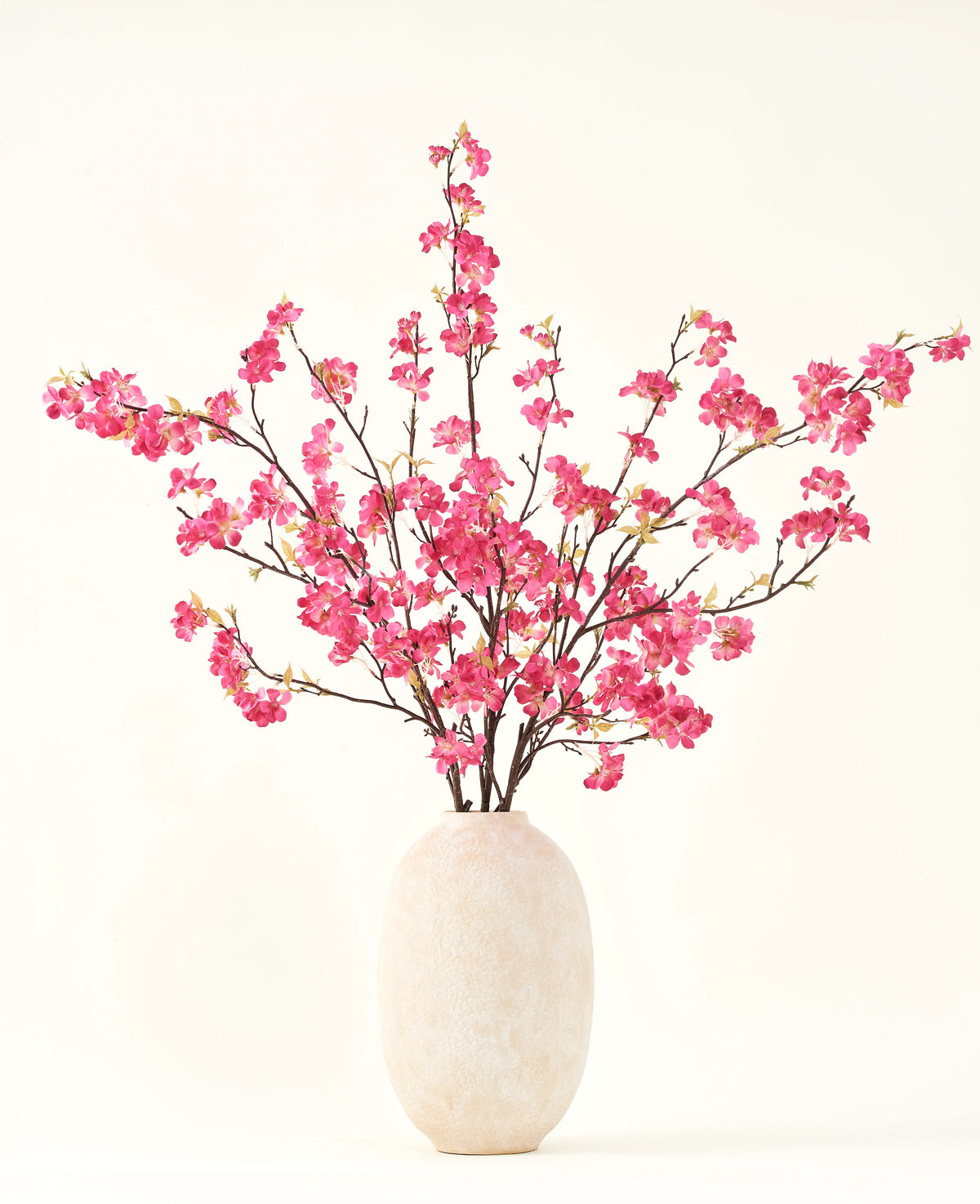 Silke kunstige blomsterbuketten Cherry blossom fuchsia 150 cm har livlige fuchsia kirsebærblomststængler med grønne blade i en simpel hvid vase, som vil komplementere ethvert interiør på en lys baggrund.