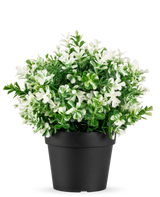 Den Kunstige Plante Firkløver hvid UV 22 cm er en sort urtepotte med kunstige grønne blade og små hvide blomster på en almindelig hvid baggrund.