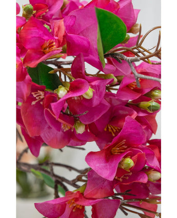 Close-up van de Kunstbloem Bougainvillea 90 cm paars, met levendige paarse bloemblaadjes, groene bladeren en dunne bruine stelen met gedetailleerde geelgroene hartjes voor een realistisch bloemenaccent.