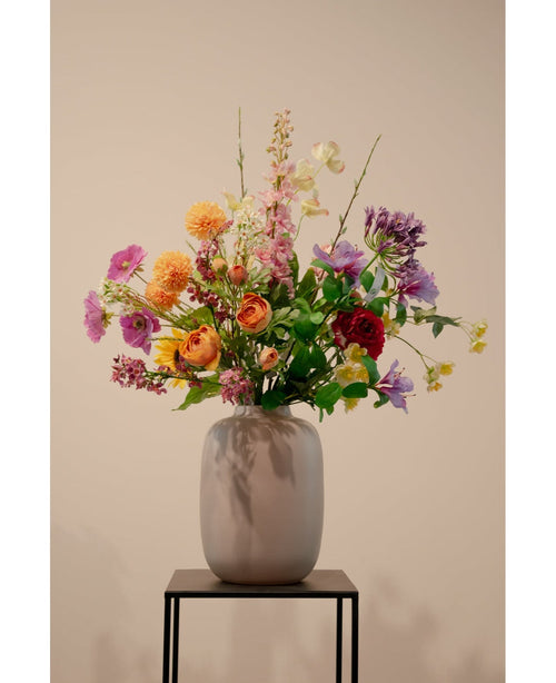 The Artificial Dogwood Real Touch Light Yellow 74cm, en naturtro lysegul kunstig blomst, står i en keramisk vase med grønt løv på et sort metalstativ mod en almindelig beige baggrund.