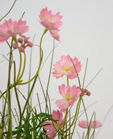 Artificial Grass Pink Gesang Flower Onion Grass Pot 56cm Brandhæmmende har sarte lyserøde blomster med slanke grønne stængler og smalle blade, arrangeret mod en lys baggrund for en blød, luftig effekt.