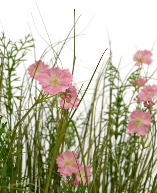 Artificial Grass Pink Gesang Flower Onion Grass Pot 90cm Brandhæmmende har lyserøde blomster med et lysegrønt hjerte, der blomstrer blandt højt, tyndt græs og frodige løvplanter, alt sammen mod en hvid baggrund.