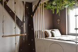 Een gezellige kinderslaapkamer met een ingebouwd bed en kussens is versierd met de Kunsthaag Lush Deco Deluxe 100x100 cm UV, die weelderig groen toevoegt. Een klimmuur, touwladder en schommel creëren een boomhutgevoel bij daglicht.