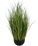 De Kunstgras Dogtail uiengras Bran 90cm is een groene kunstgrasplant met lange, smalle bladeren in een ronde zwarte pot, brandvertragend, tegen een effen witte achtergrond.